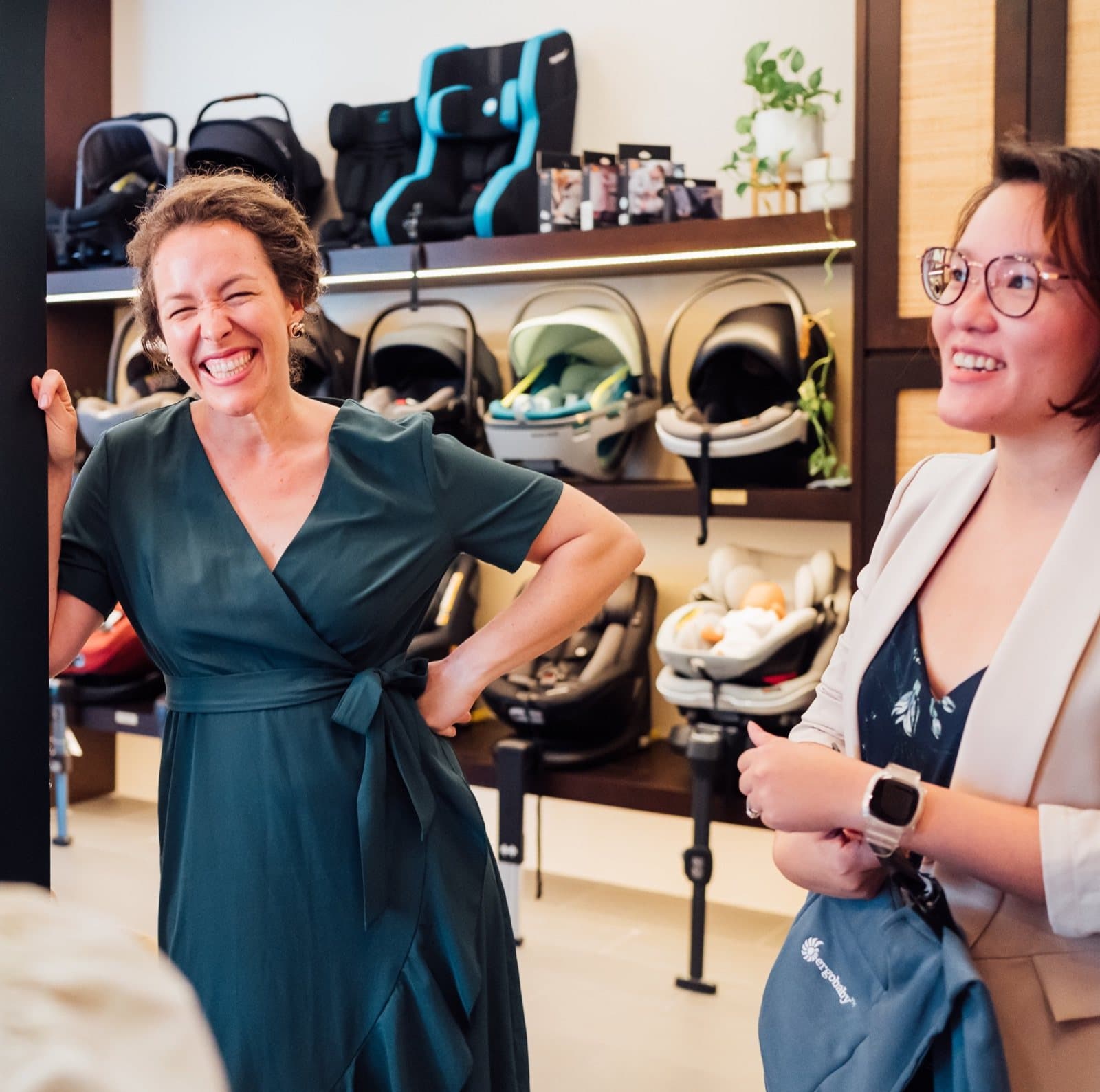 Two women mid-conversation in the Pramfox showroom, shelves of car seats behind them