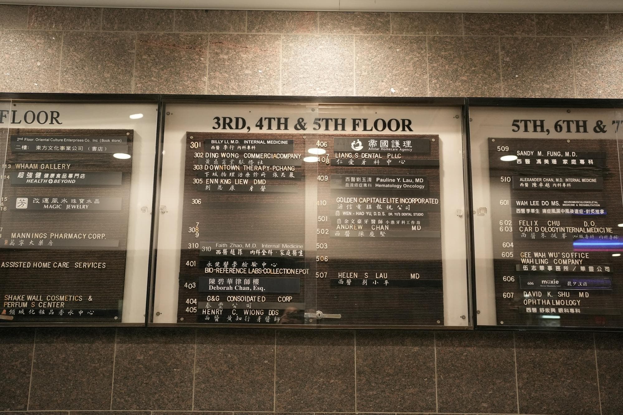 A glass-fronted building directory in Hong Kong, every tenant listed by floor in English and Chinese
