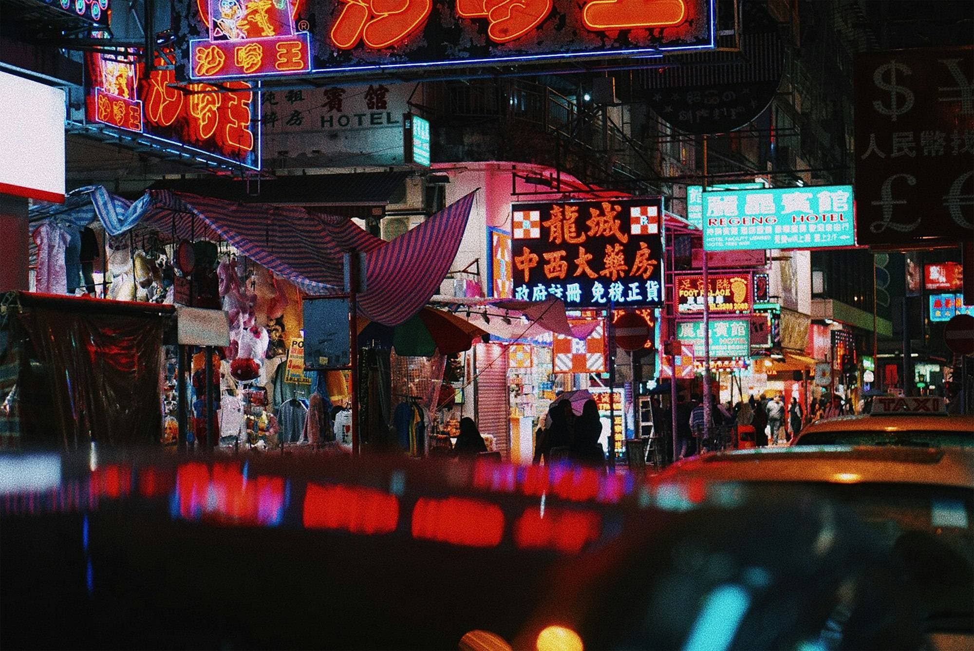 Neon shop signs crowding a Hong Kong street at night