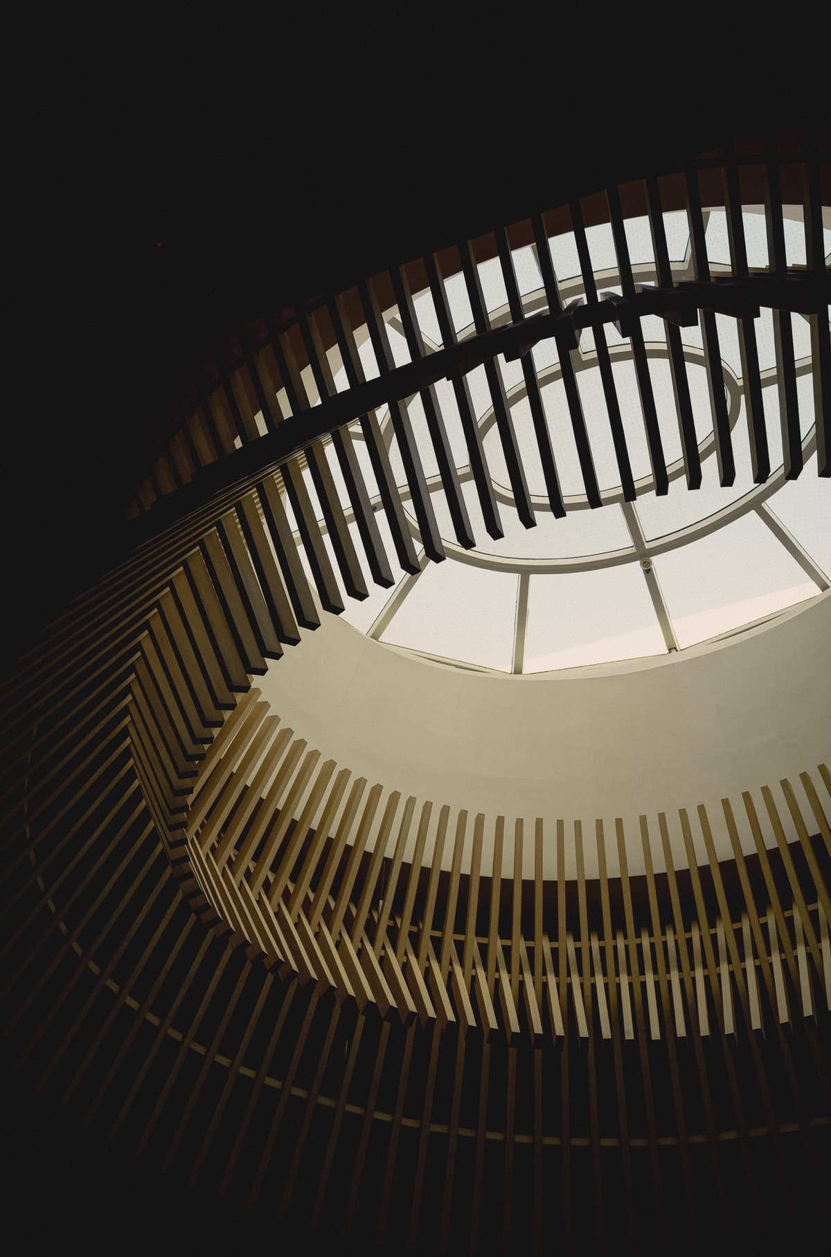 A spiral atrium of timber slats opening to a skylight at The Upper House, Hong Kong