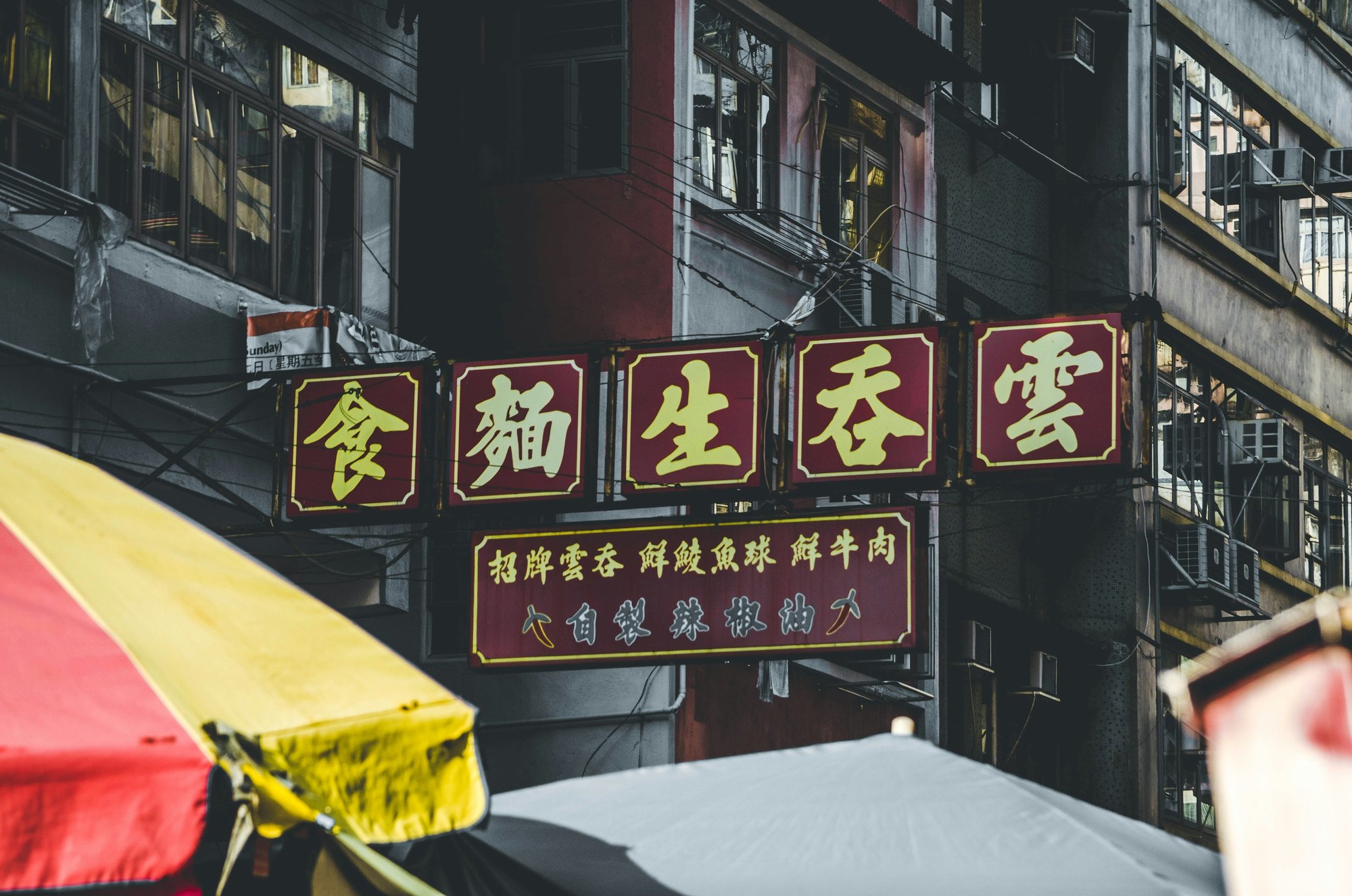 A wonton noodle shop's sign in Hong Kong, gold Traditional characters painted on a lacquered red board