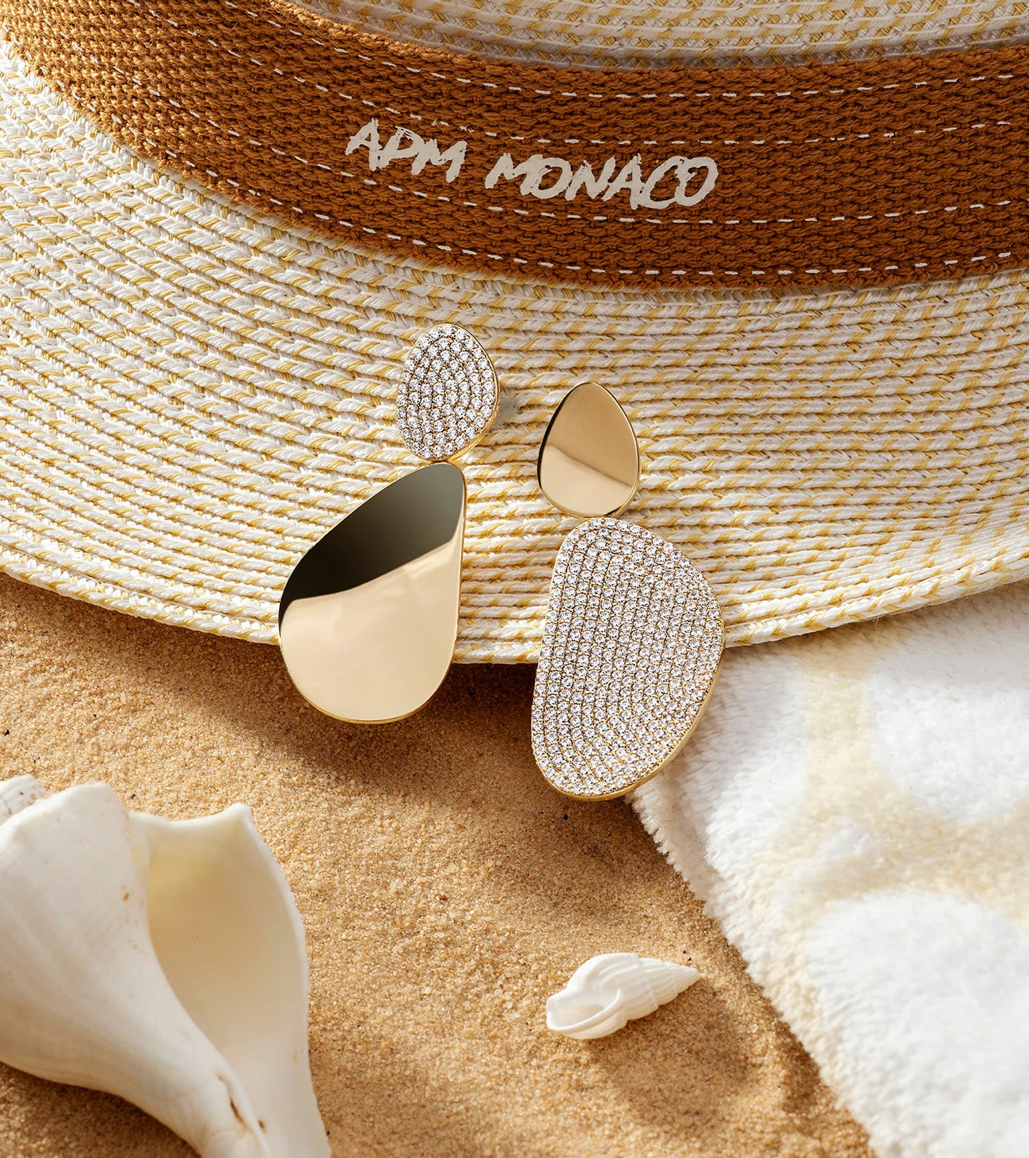 APM Monaco Galté gold and pavé earrings on a straw hat in the sand