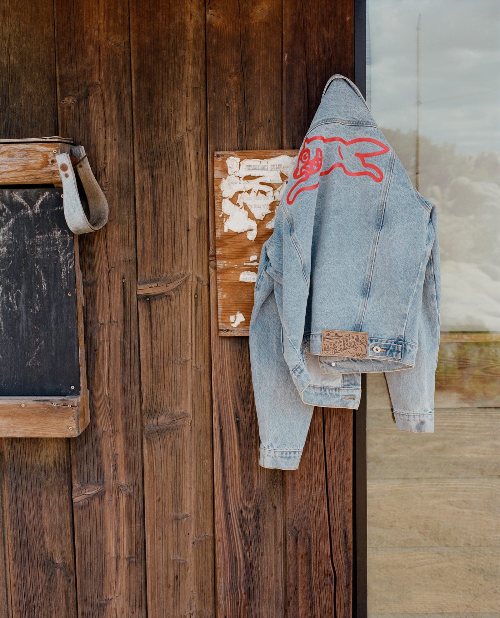 A Billionaire Boys Club denim jacket hung on a wooden wall