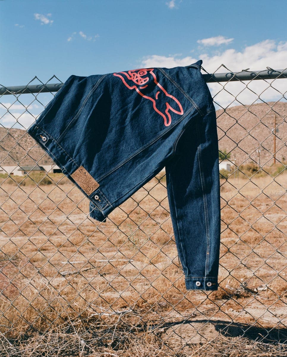ICECREAM jeans hung on a chain-link fence