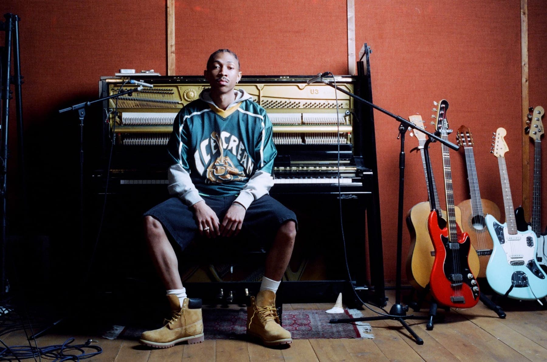 A Billionaire Boys Club look at an upright piano, guitars racked beside it