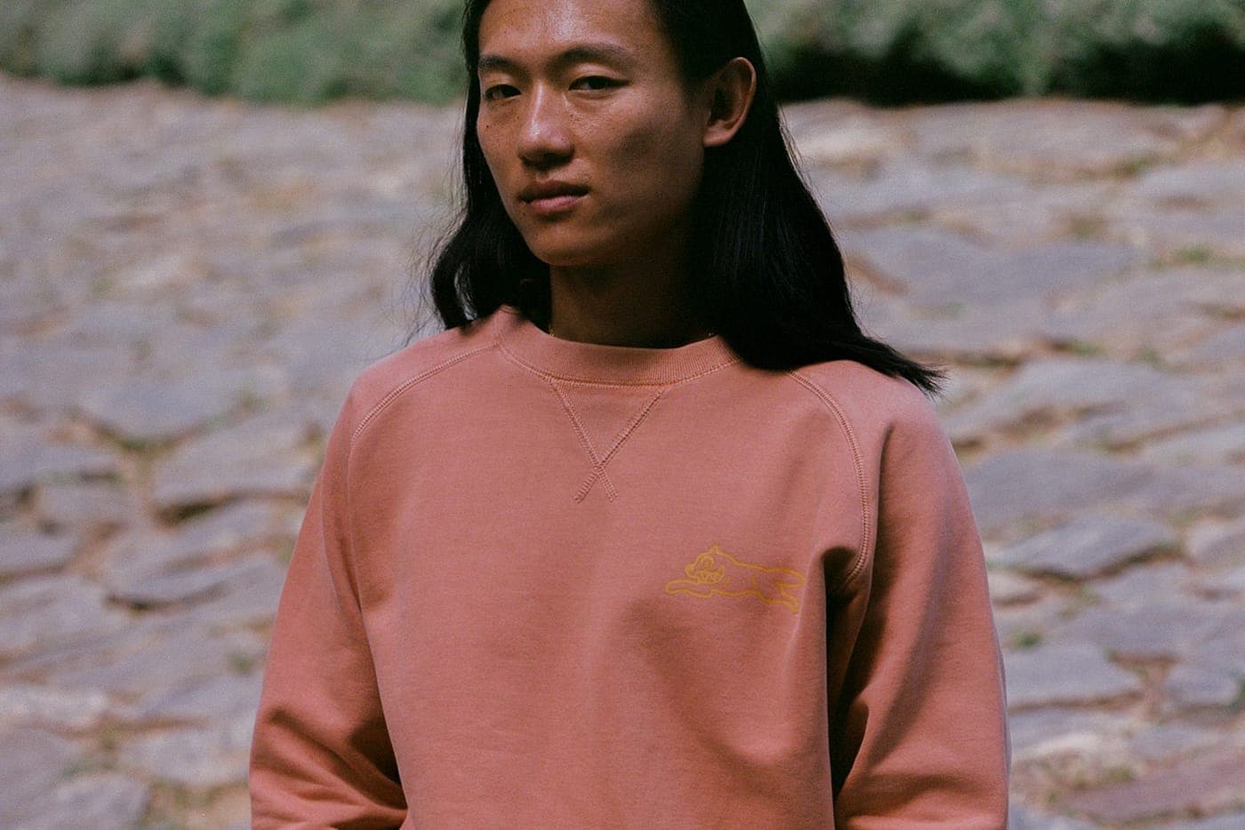 A pink Billionaire Boys Club crewneck on a cobbled street