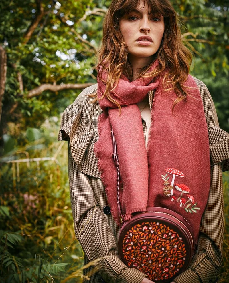 A model in a Fable England mushroom-embroidered scarf, carrying a matching round bag