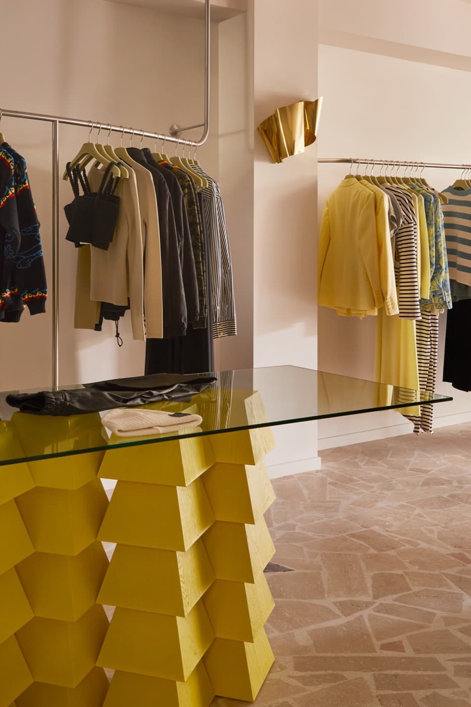 A sculptural yellow display table beside the clothing rails at Grace Brighton