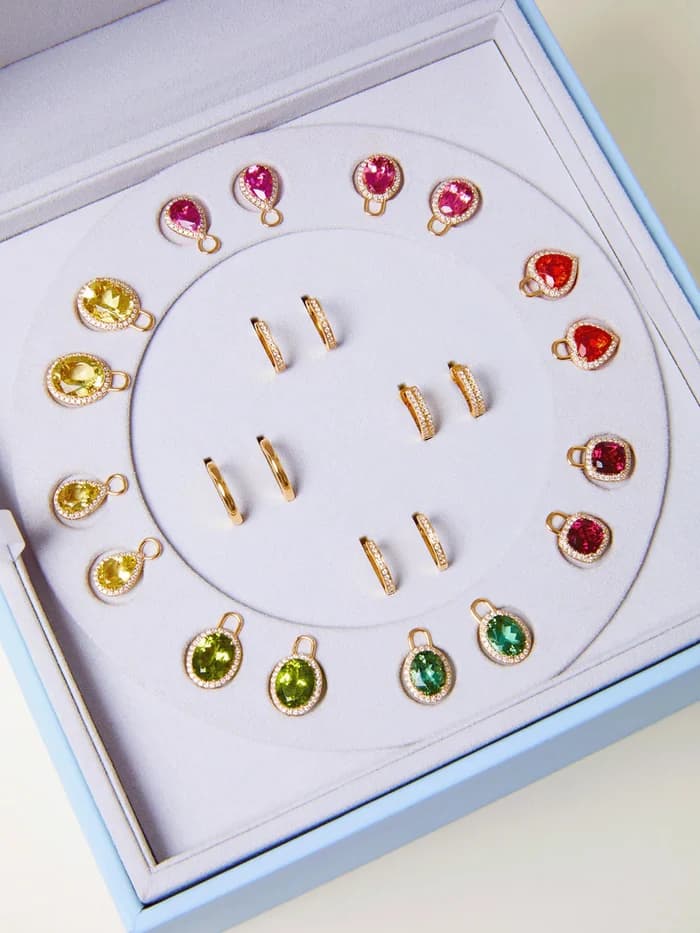 A Kiki McDonough jewellery box of coloured gemstone charms and hoop earrings