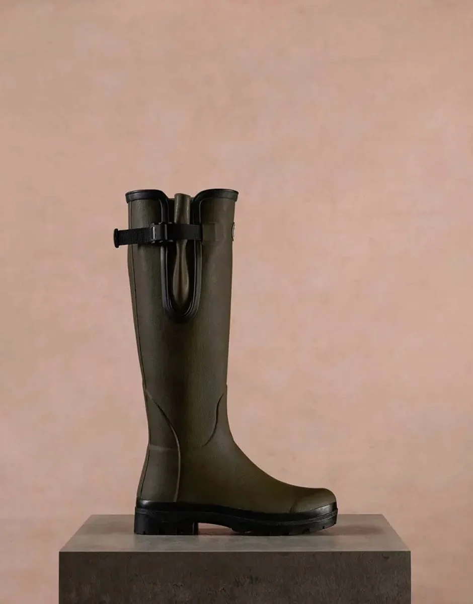 A single Le Chameau wellington boot on a stone plinth against a blush backdrop