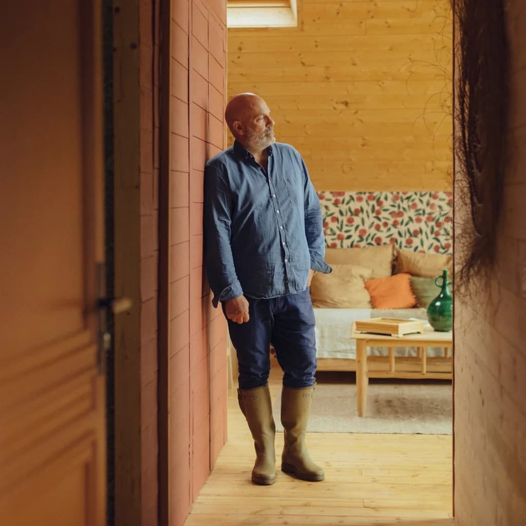 A man in Le Chameau boots in the doorway of a wooden cabin