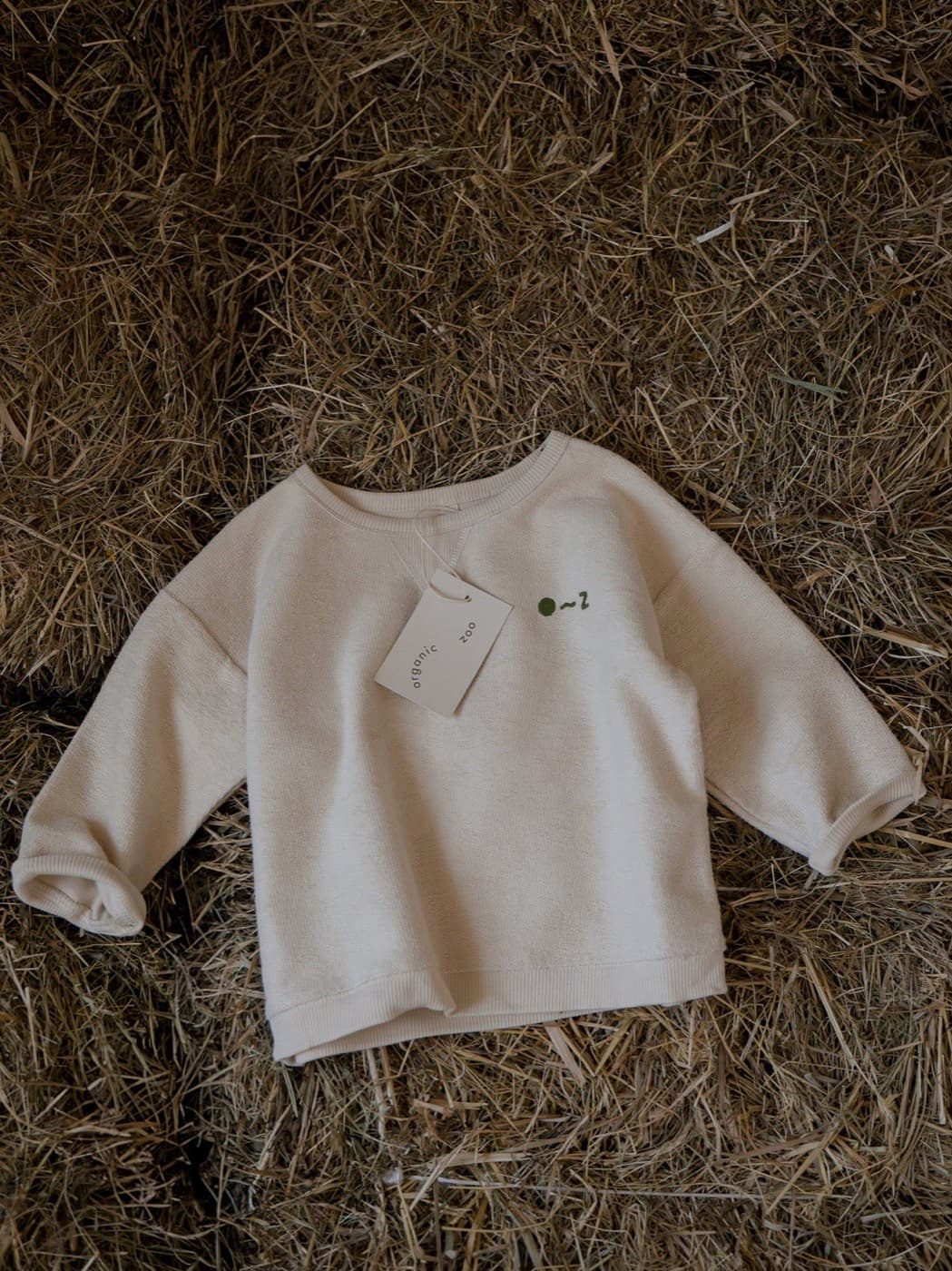 An Organic Zoo undyed cotton cream sweatshirt laid on straw