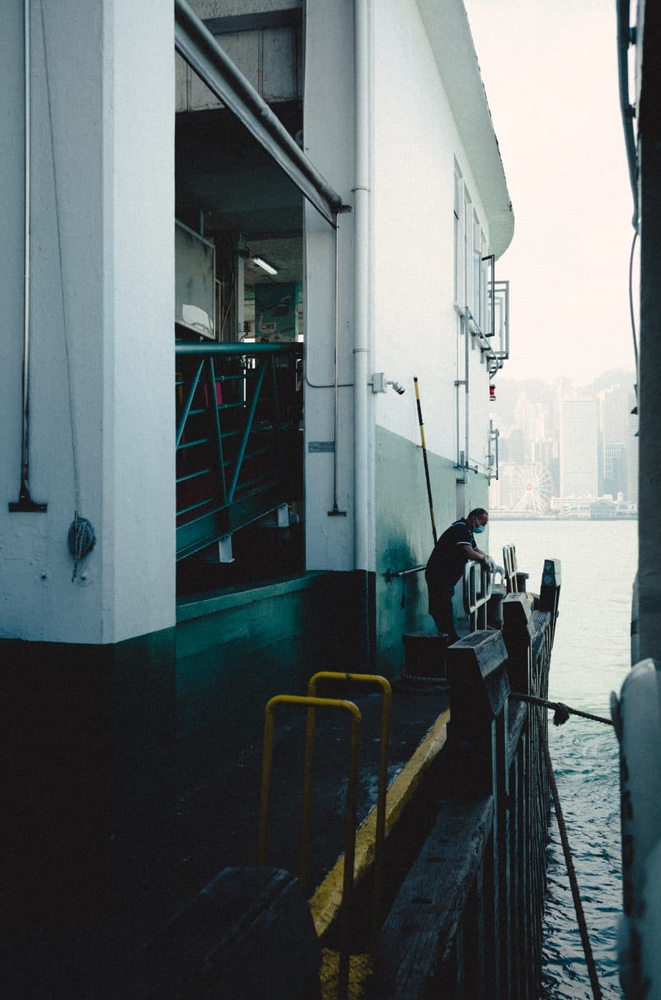 A Star Ferry deckhand at the pier, Victoria Harbour behind