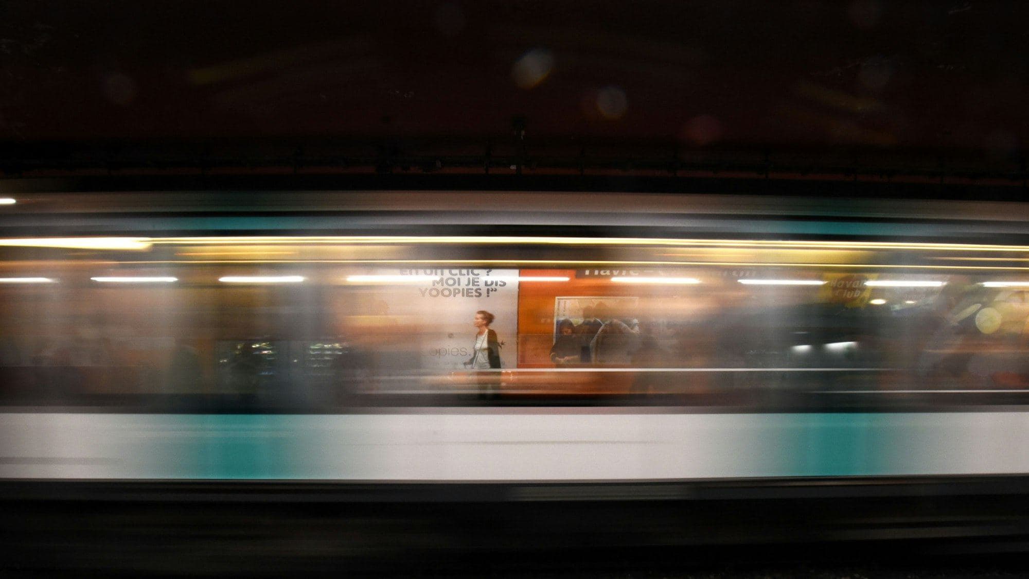 A metro train blurred with speed as it passes a platform